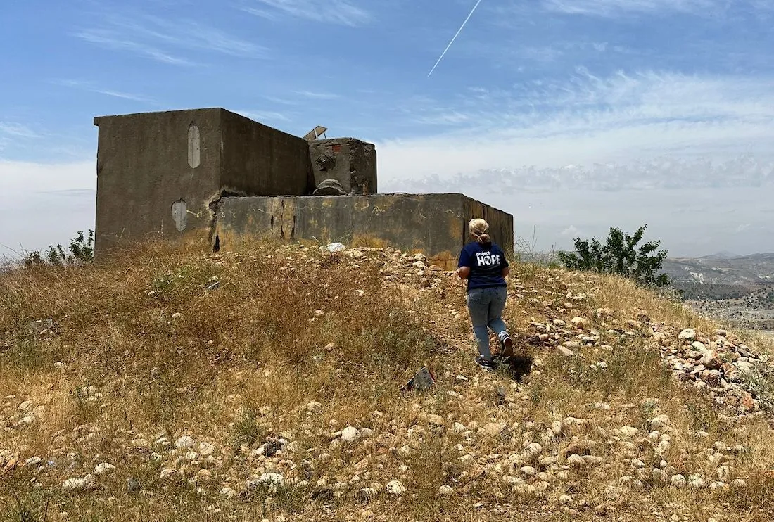 woman running up hill to a damaged home