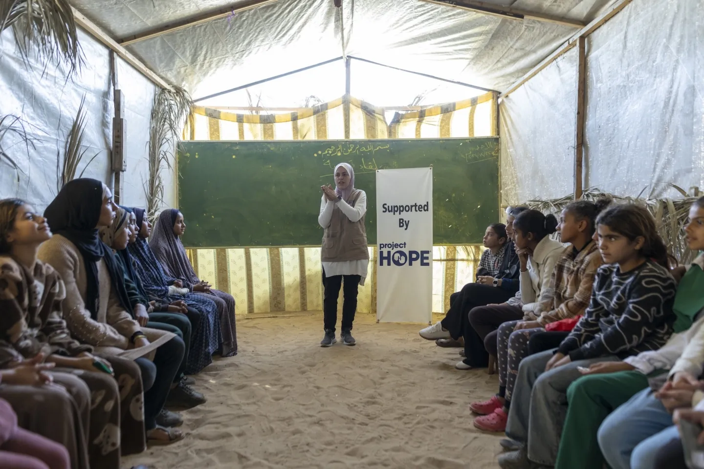 woman stands in front of group of children to discuss mental health