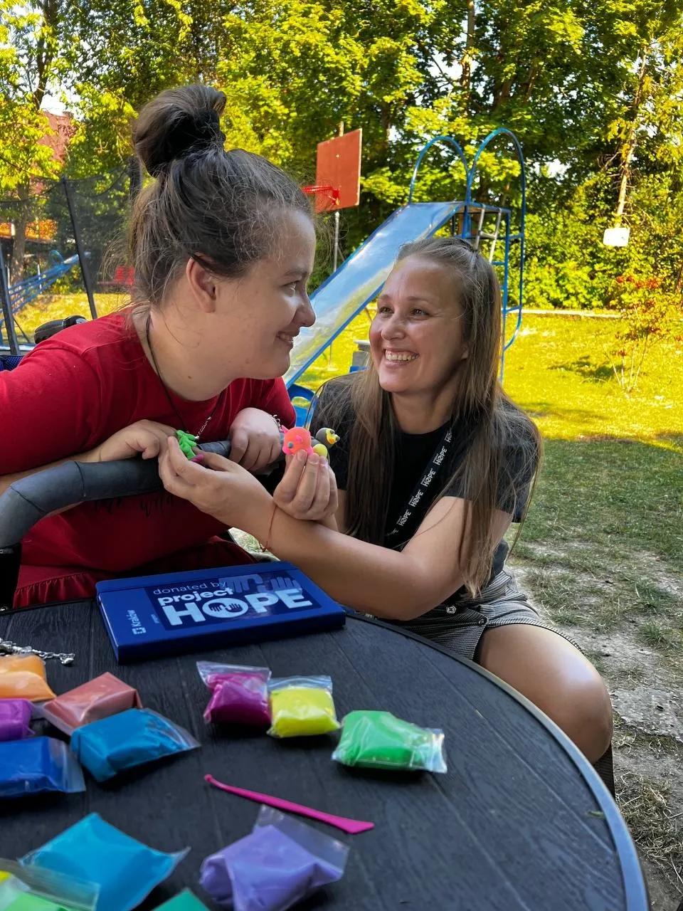 girl in wheelchair smiles to a woman