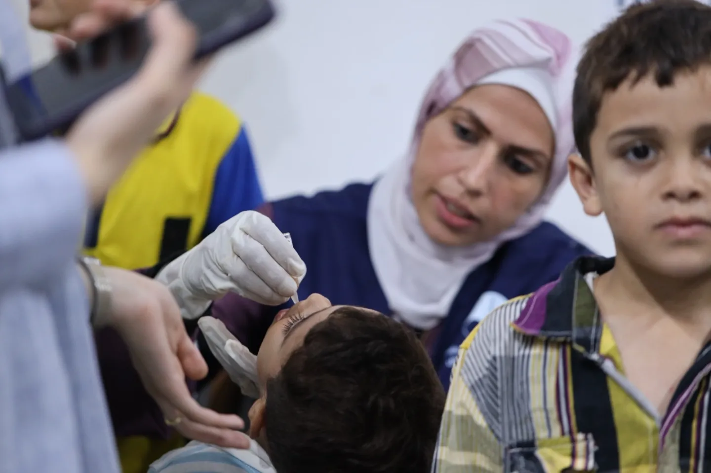 A medical staff person distributes an oral polio vaccine to a young child in Gaza