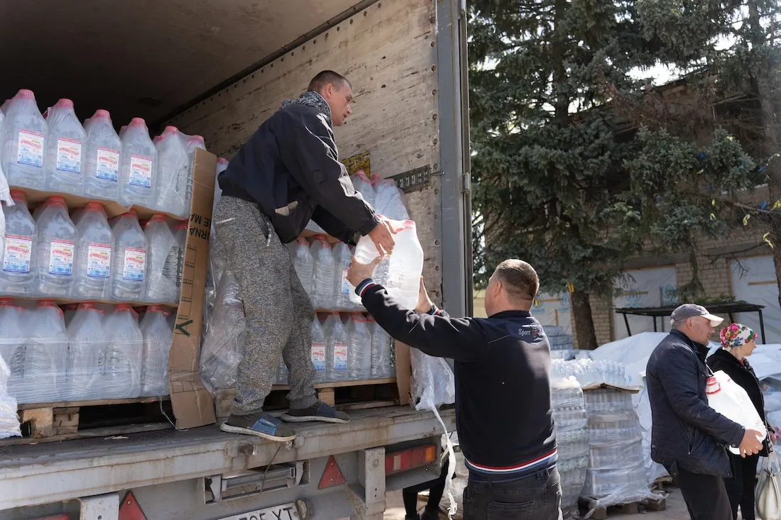 two men moving water jugs from a truck