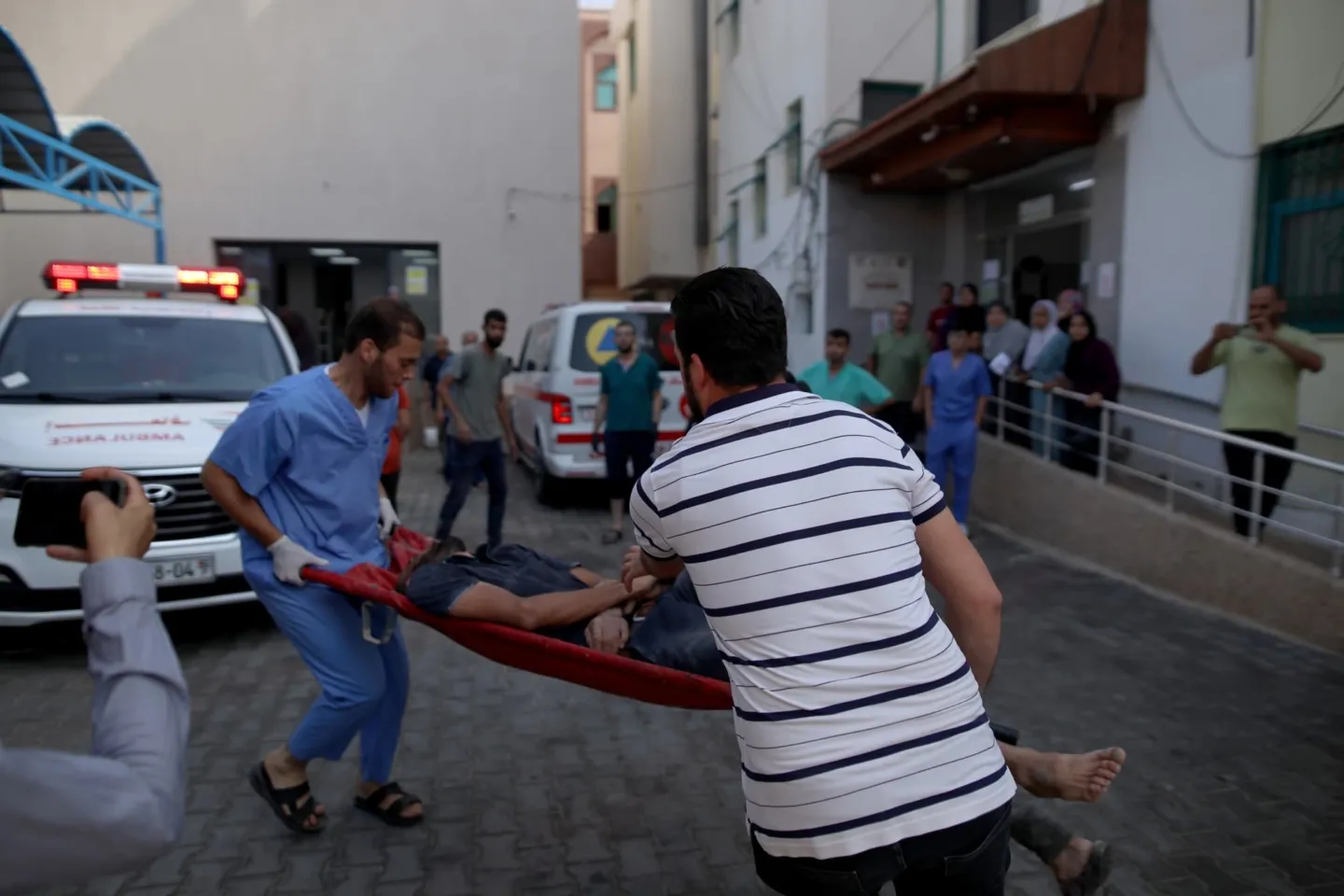 Two men carrying an injured man in a gurney in Gaza