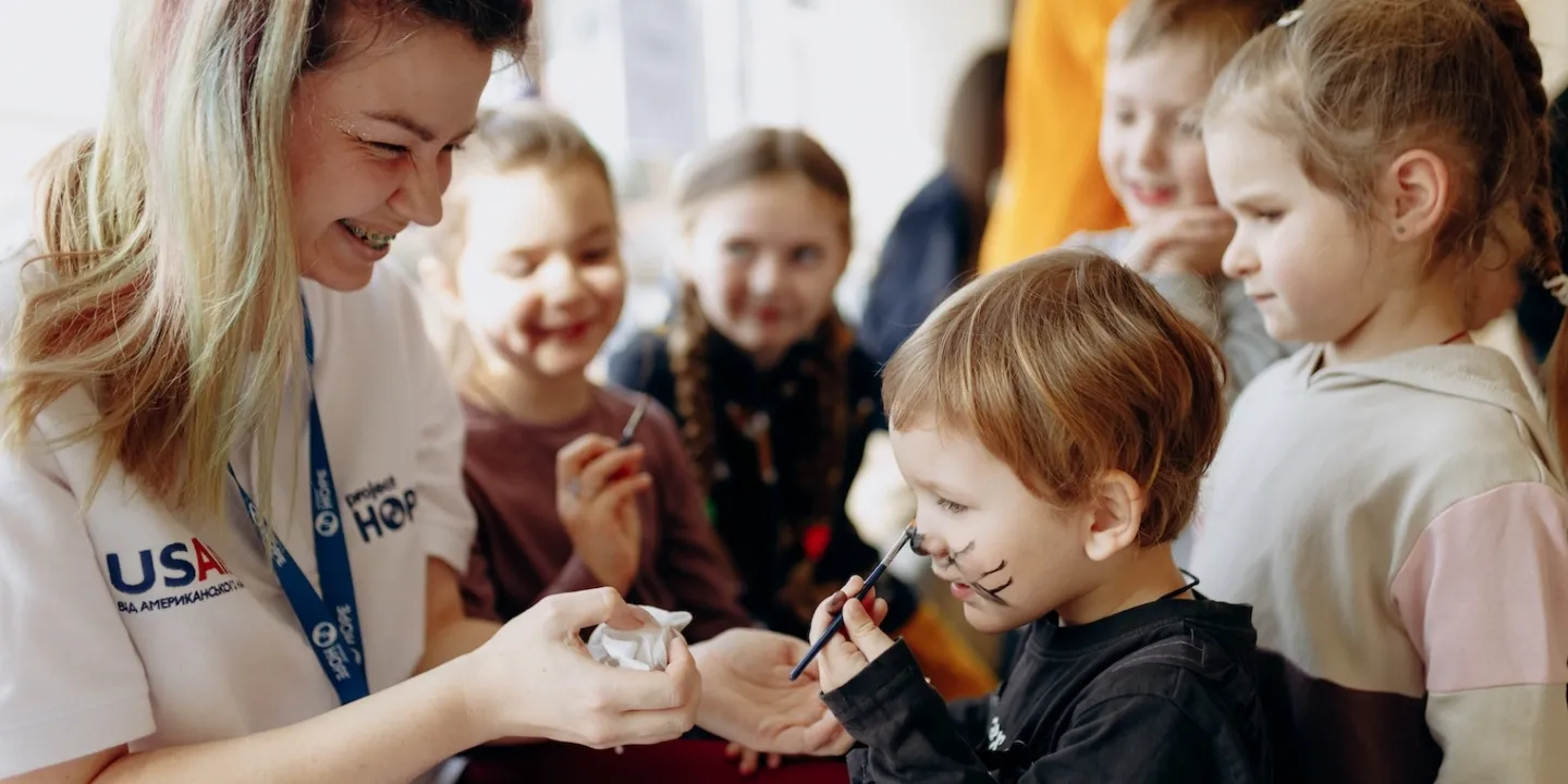 woman face paints young boy