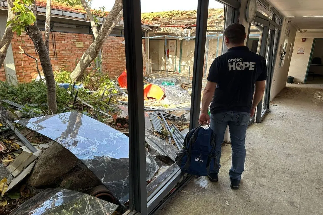 Man in Project HOPE shirt walks through rubble