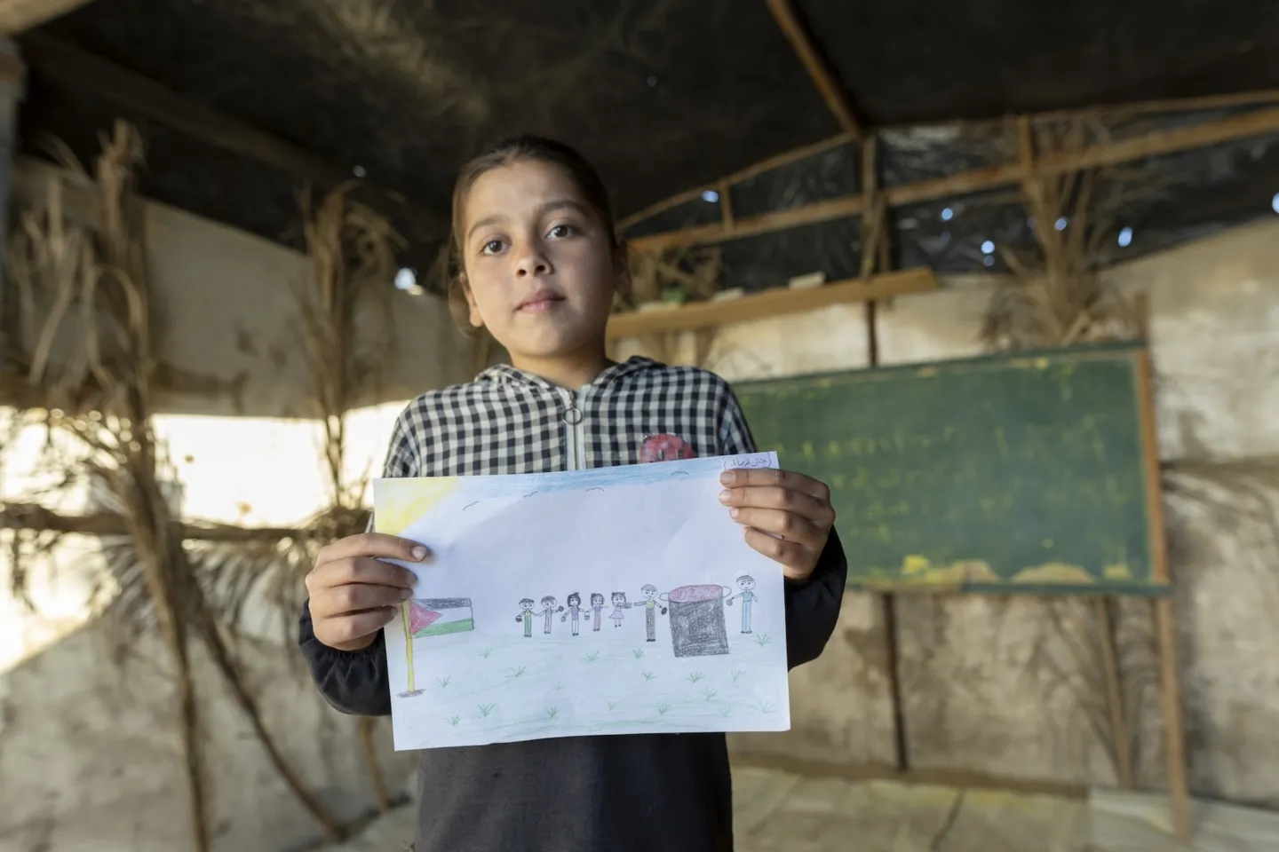young girl shows off artwork in Gaza camp
