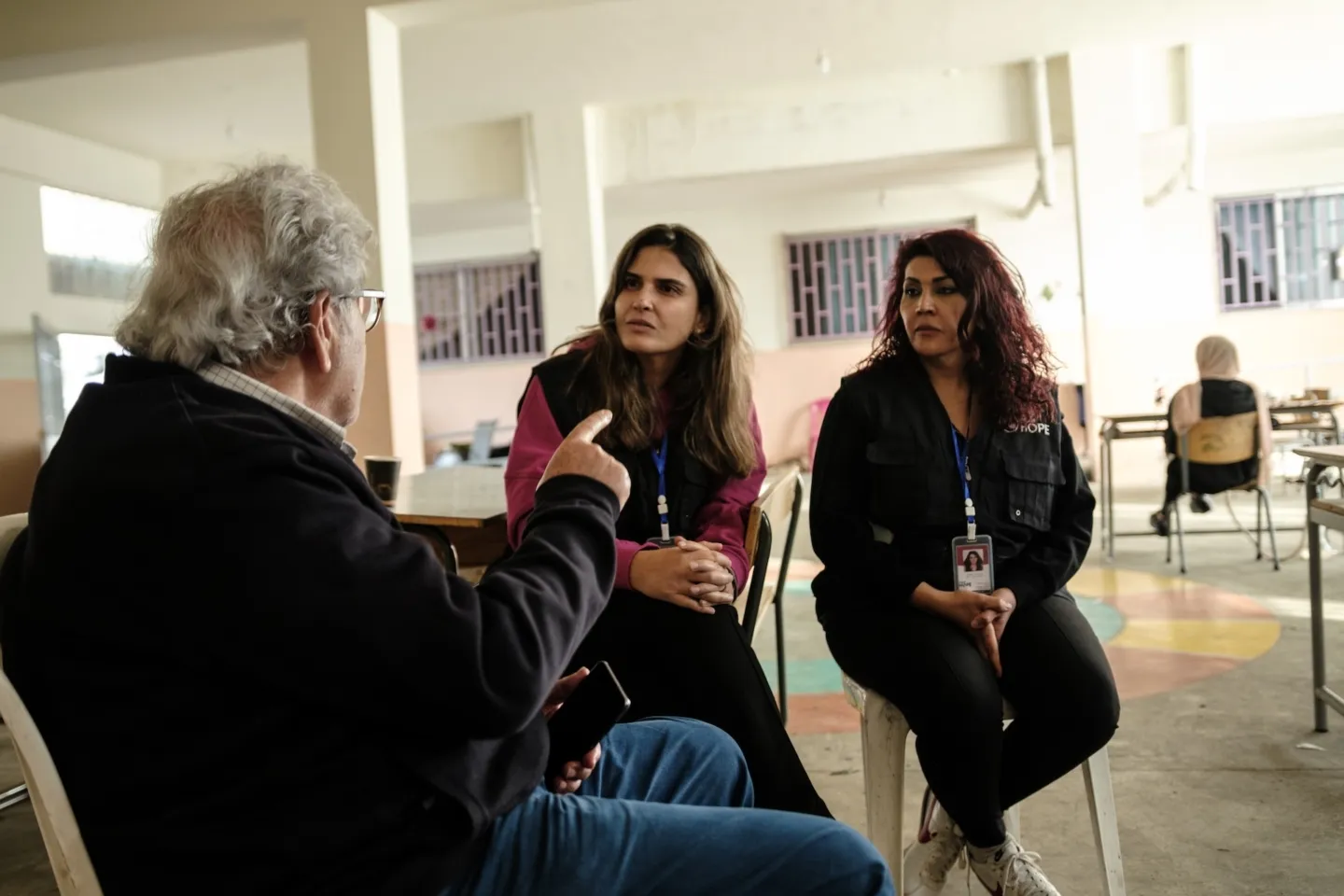 Two women speaking with an elderly man in Lebanon