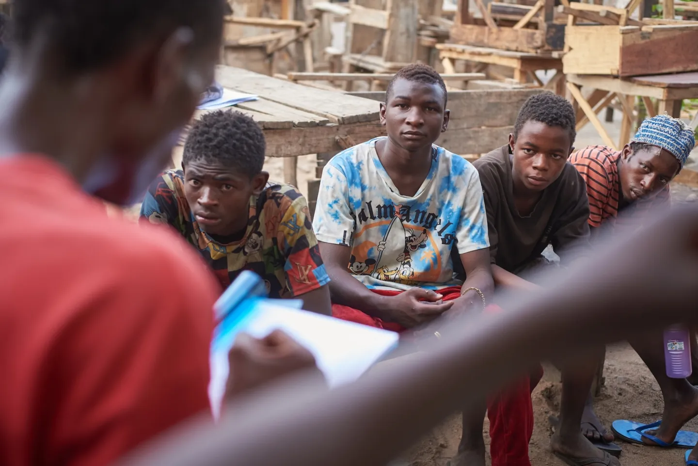 over the shoulder of someone, we see four young teenage boys listening to leader