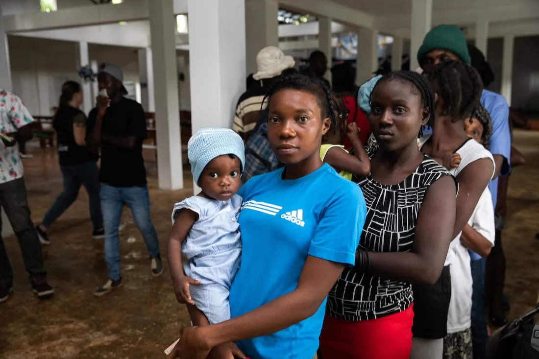 two women standing next to each other and holding babies.