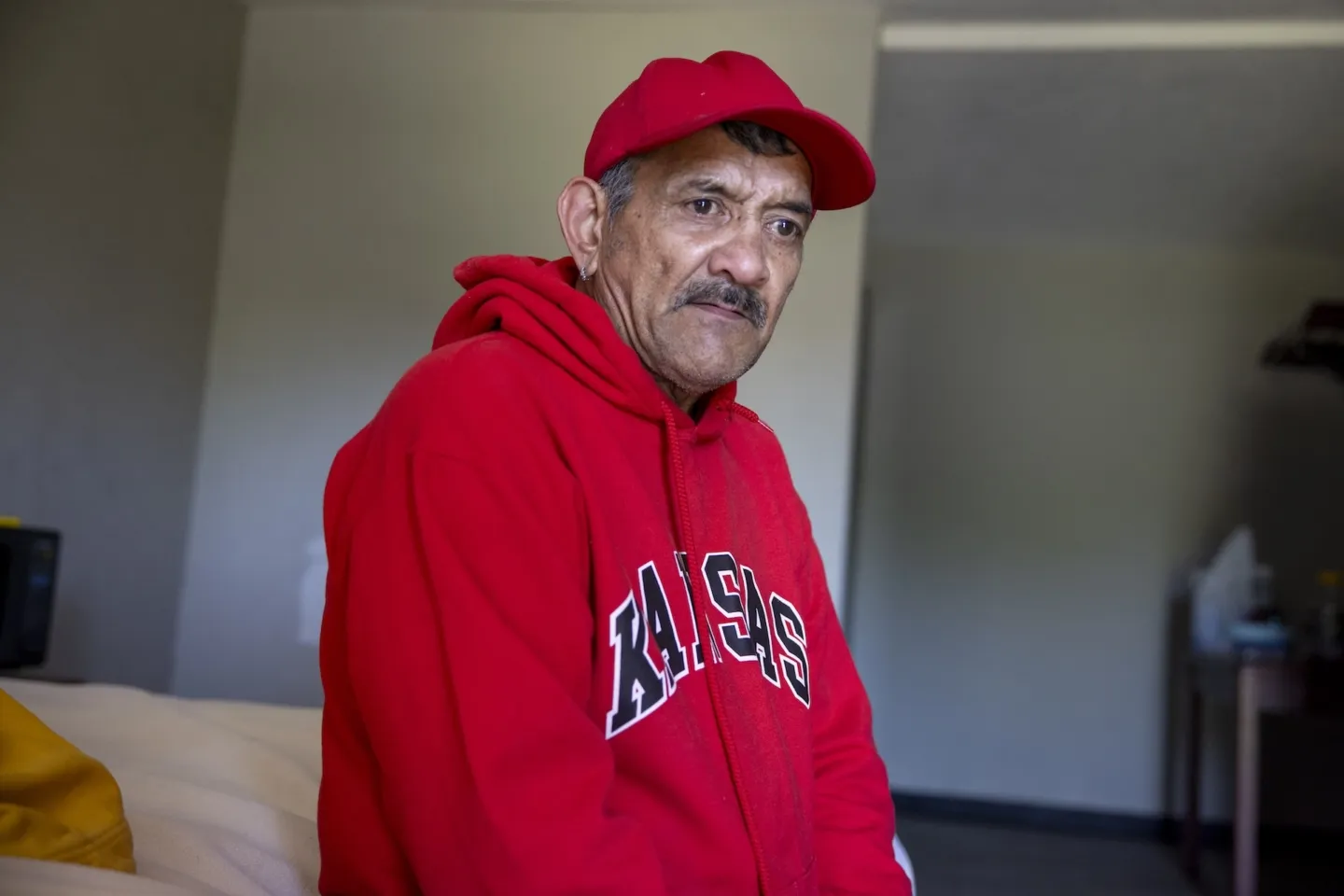 Man in a red hat and red sweatshirt sitting and staring off into the distance