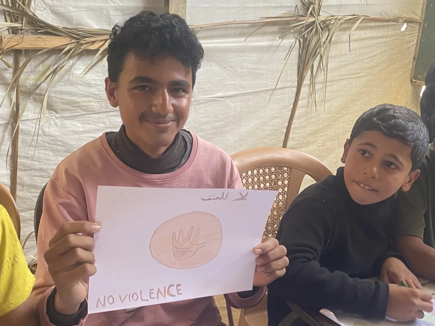 young boy shows off artwork in Gaza camp