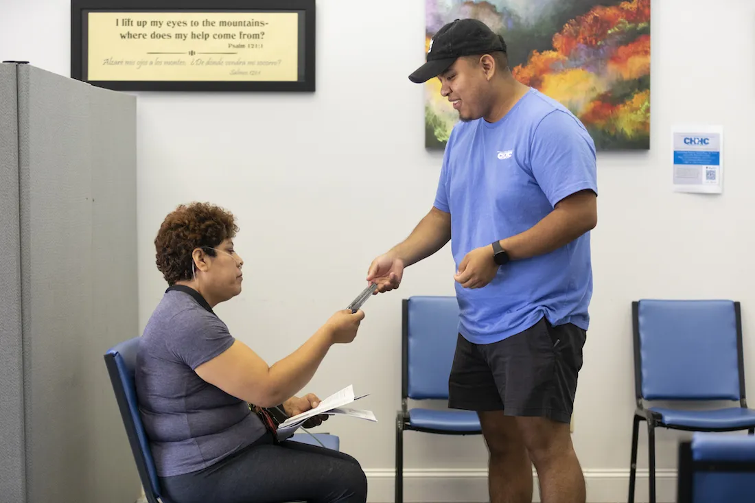 A woman breathing with an oxygen tank receives information from a man on healthcare.