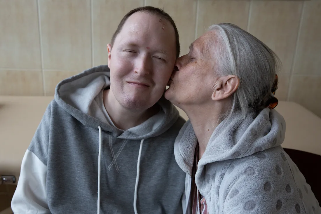 elderly mother kisses the cheek of her son