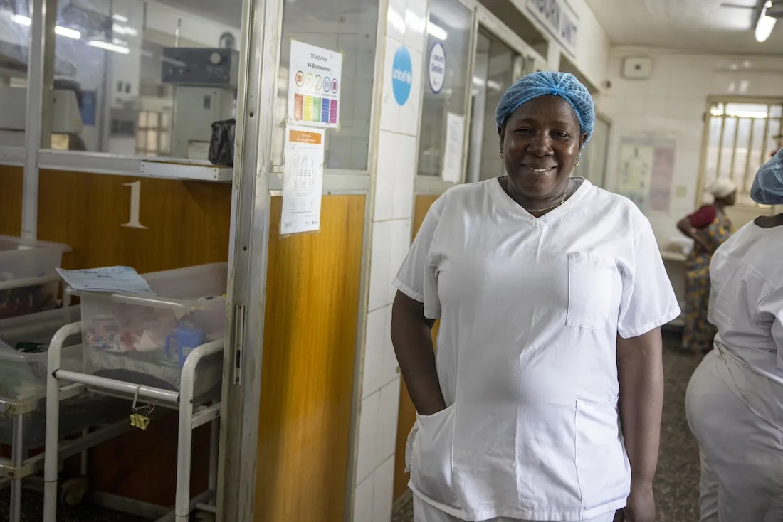 Nurse in white scrubs smiling inside of hospital