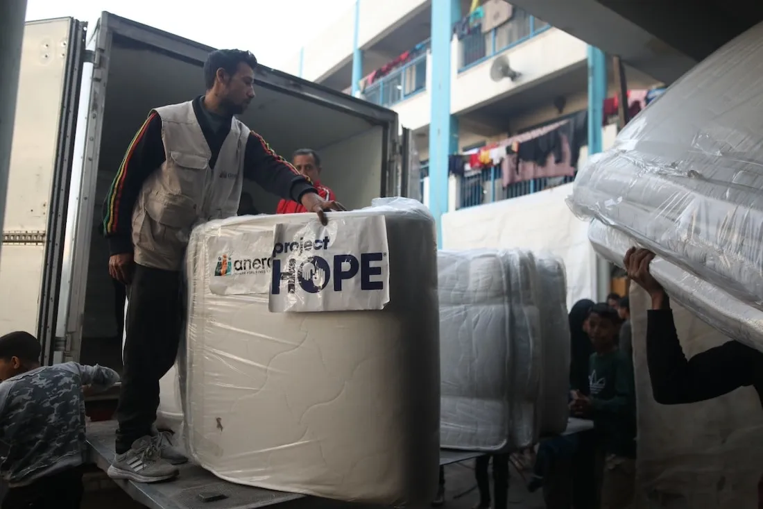 Humanitarian Aid workers distribute mattresses to displaced persons in Gaza