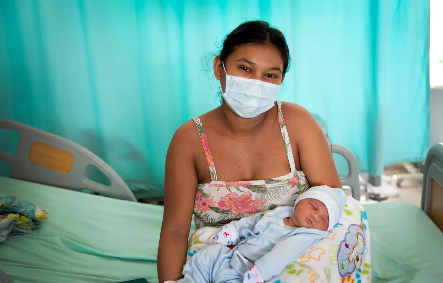 mother in a mask, holding newborn baby