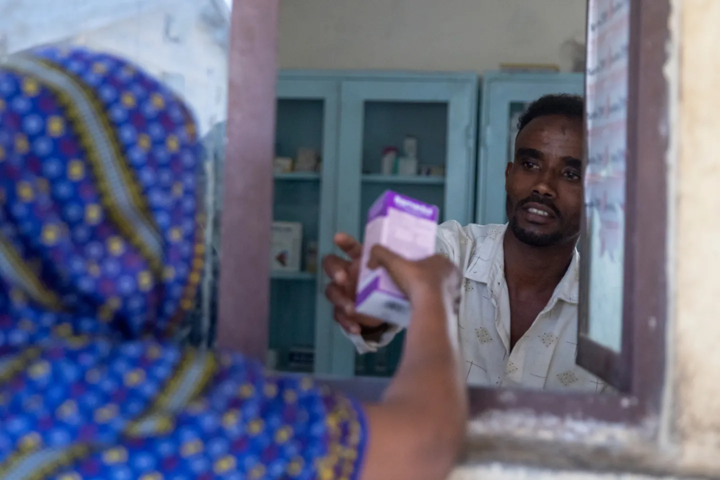 man handles medicine to woman through window