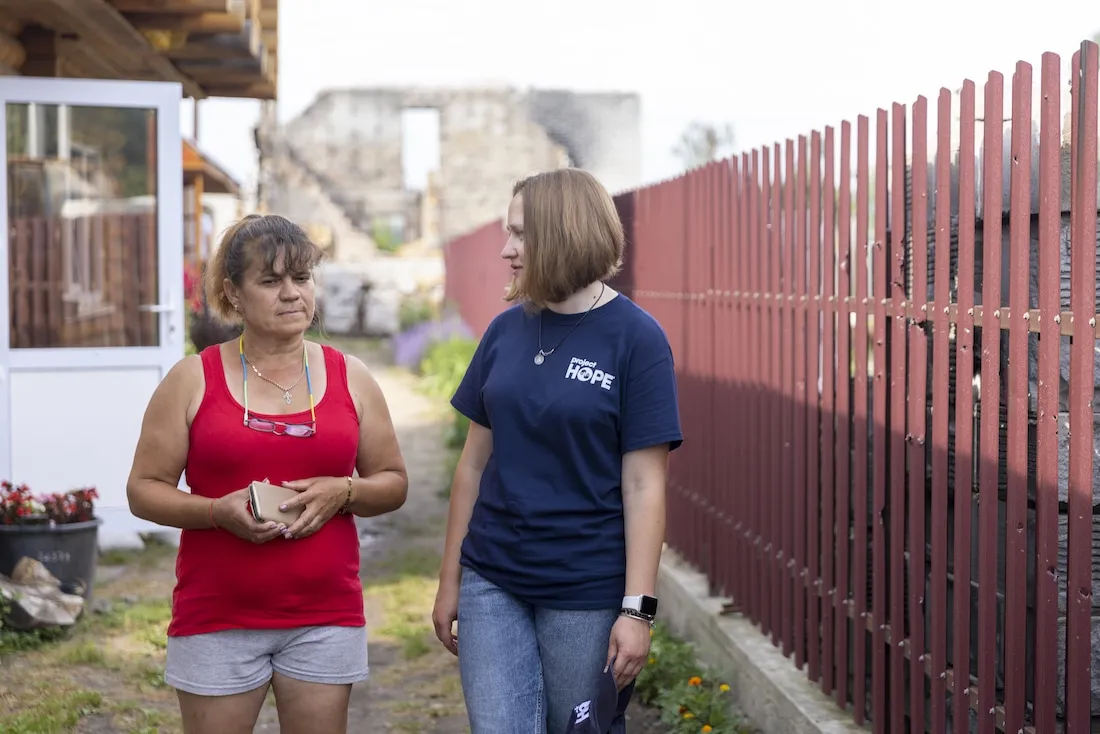 two women walking by a fence