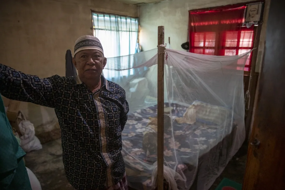 man in front of mosquito netted bed