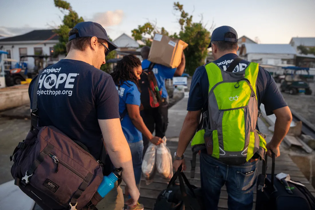 Project HOPE employees carrying supplies as they get off the boat and onto the island.