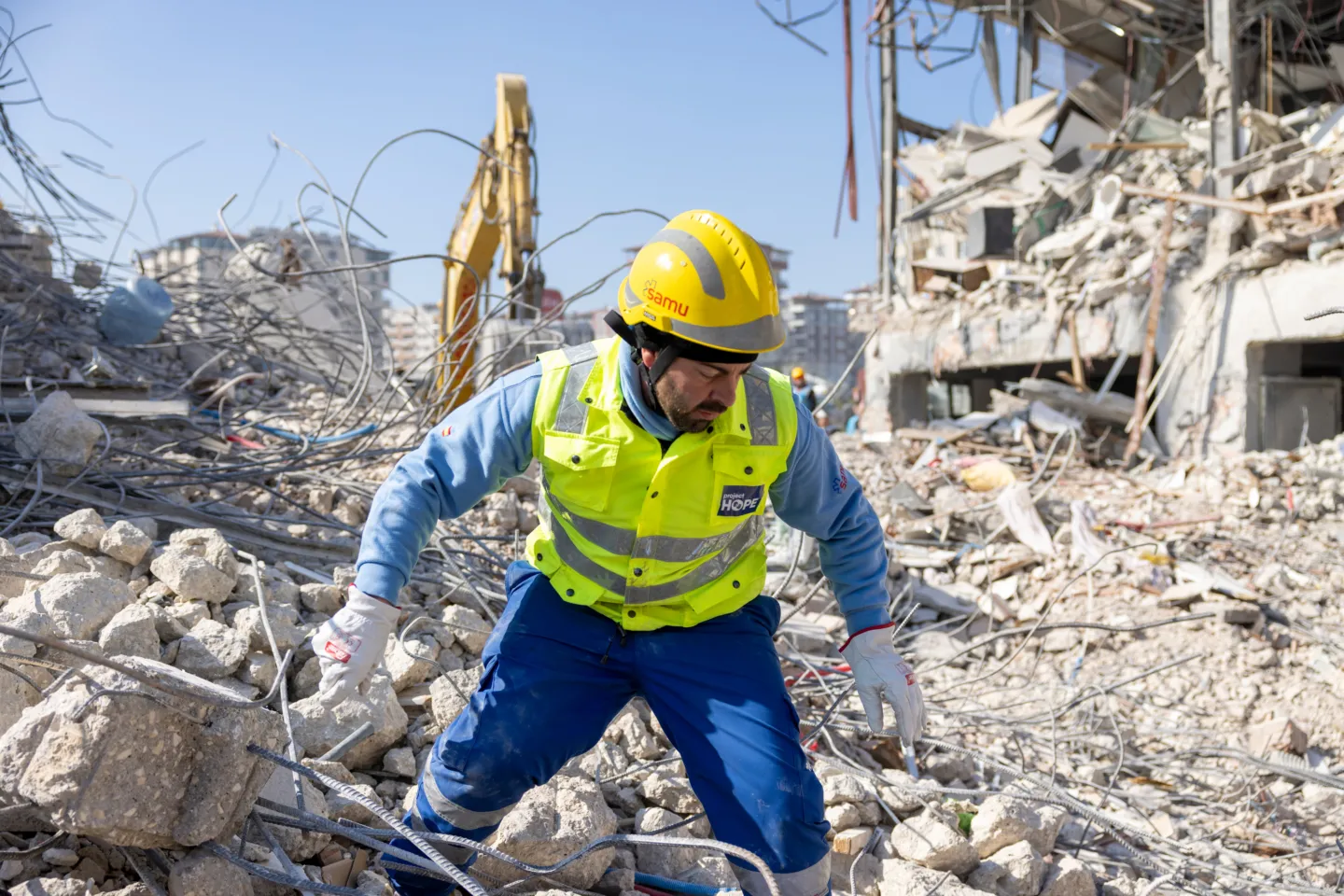 man in rescue gear and hard hat climbs through wreckage after earthquake in Turkiye