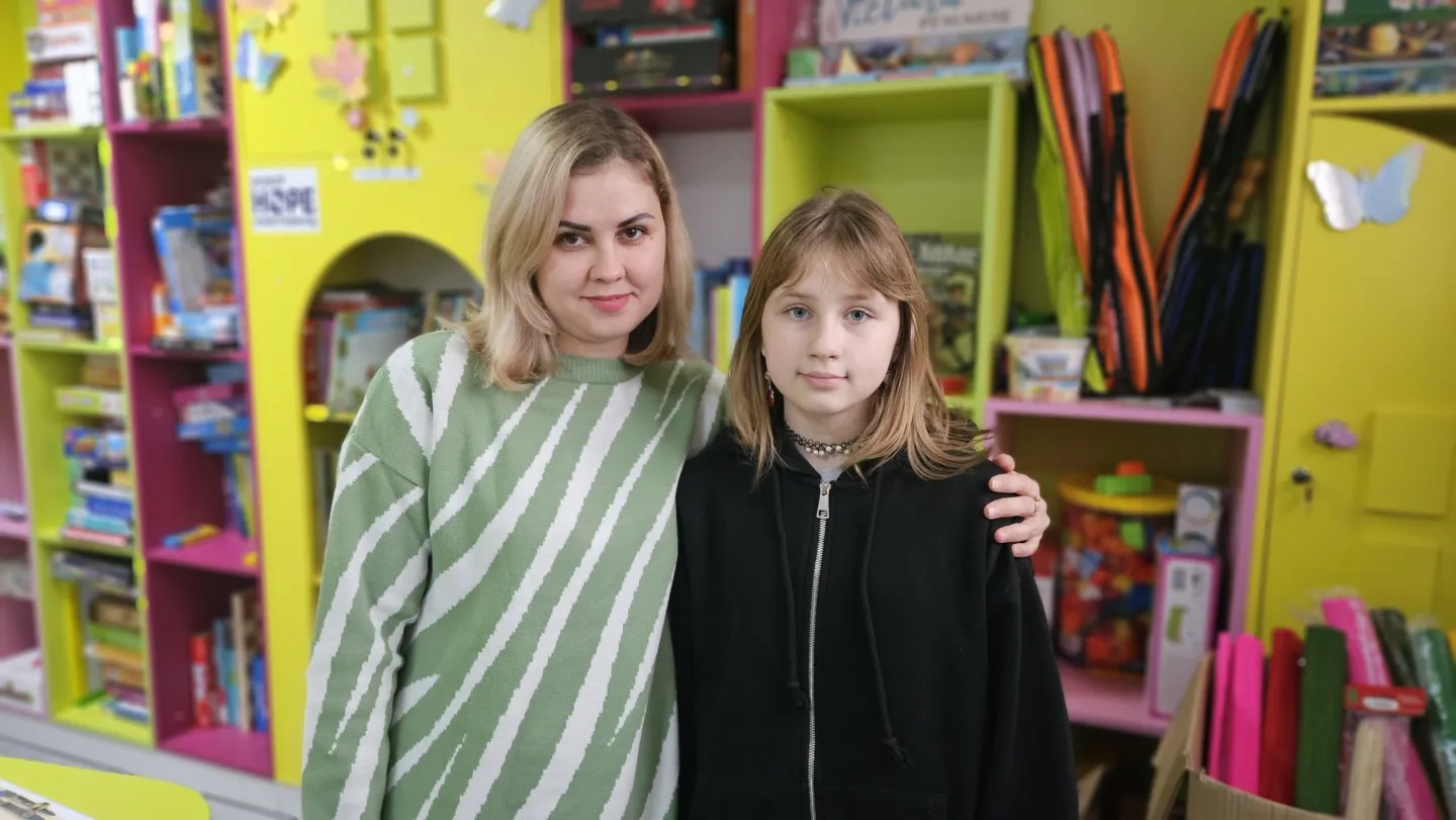 a woman stands with a young girl in a playroom