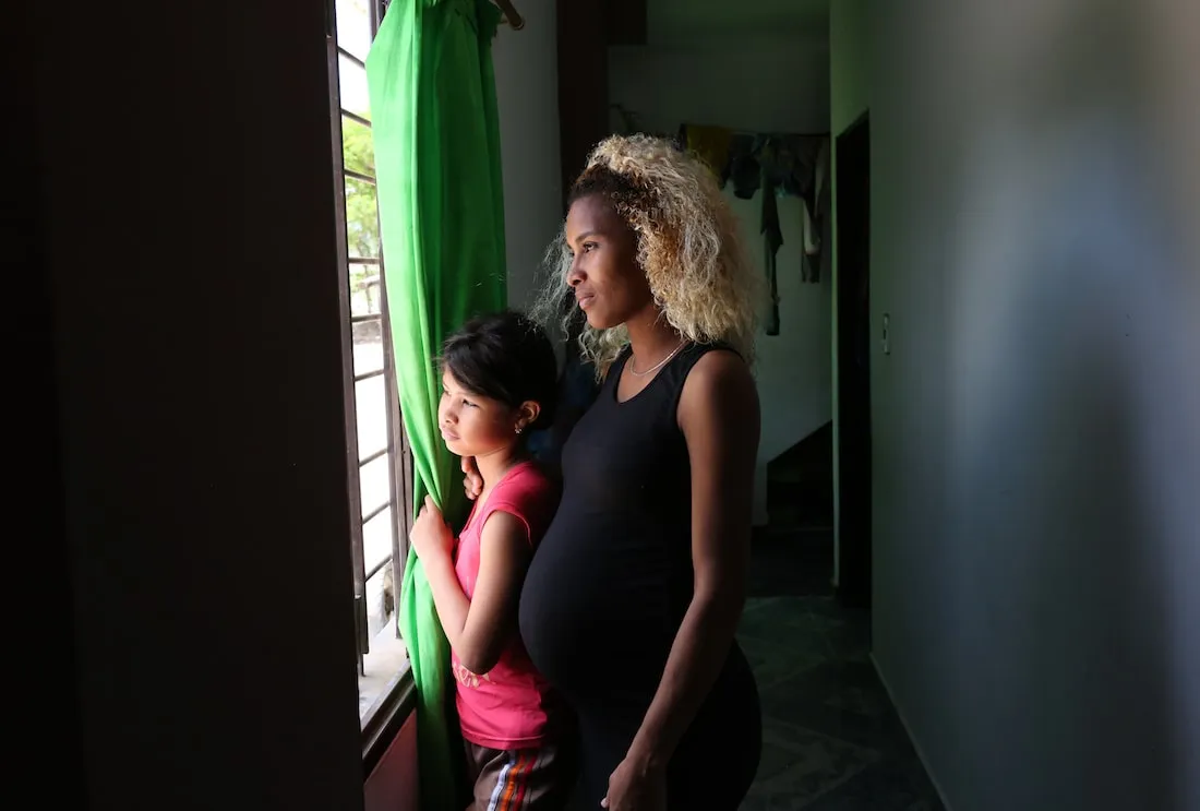 a pregnant mother and her child looking out a window