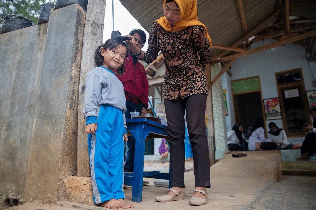 A woman measures the height of a child.