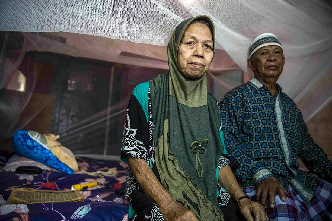An elderly couple under a mosquito net